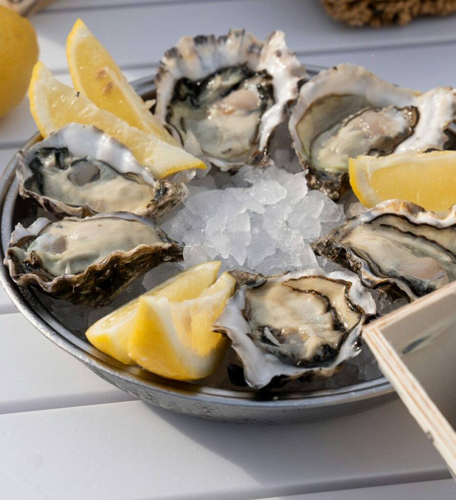 A plate of oysters with lemon wedges and ice